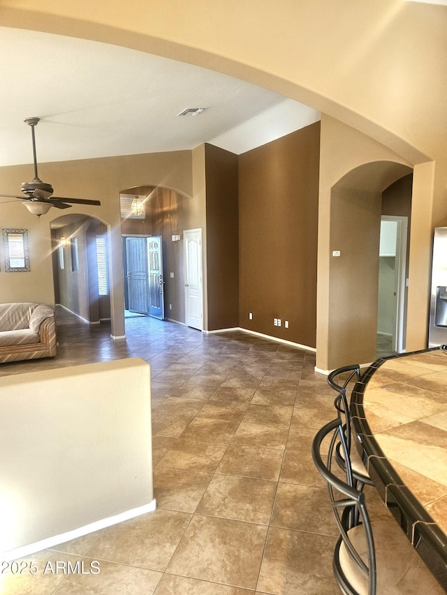 kitchen featuring stainless steel refrigerator with ice dispenser, ceiling fan, tile patterned floors, and vaulted ceiling