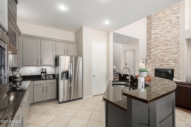 2030 W Whisper Rock Trl, Phoenix, AZ 85085 - kitchen with stainless steel fridge, gray cabinets, decorative backsplash, a large fireplace, and recessed lighting