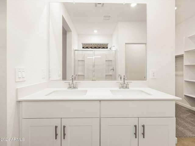 bathroom featuring double vanity, visible vents, a stall shower, and a sink