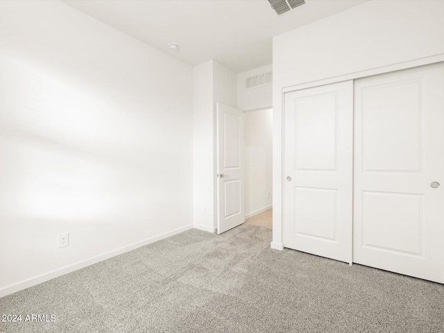 unfurnished bedroom featuring a closet and light colored carpet