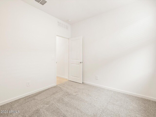 spare room with visible vents, baseboards, and light colored carpet