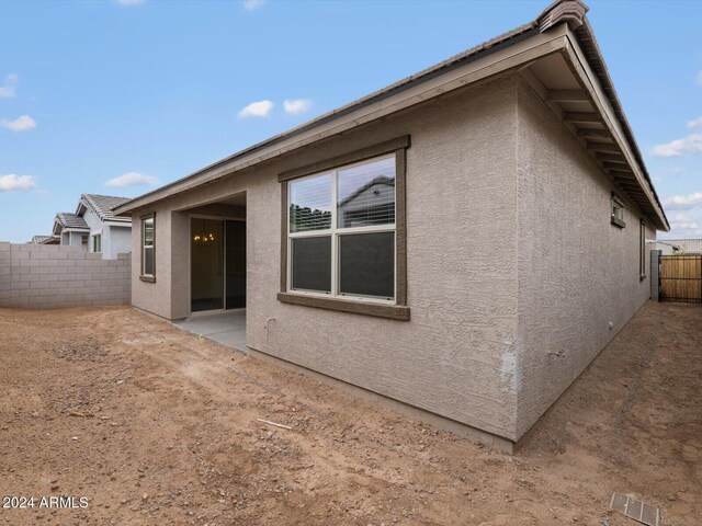 view of side of property featuring a patio area, stucco siding, and a fenced backyard