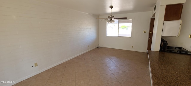 spare room with ceiling fan and brick wall