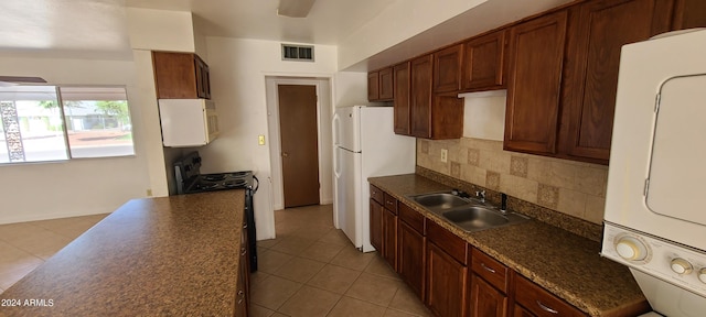 kitchen featuring backsplash, white appliances, sink, stacked washer and dryer, and light tile patterned flooring