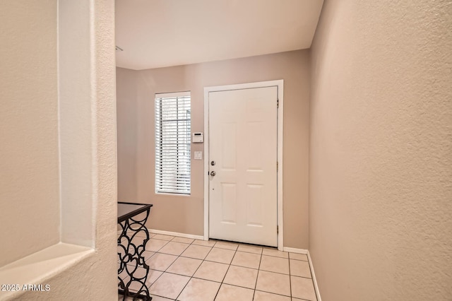 foyer with light tile patterned flooring, baseboards, and a textured wall