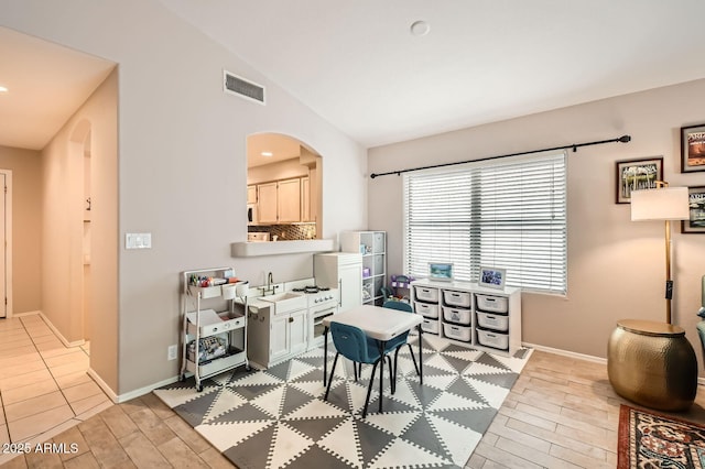 interior space with visible vents, lofted ceiling, baseboards, wood finish floors, and arched walkways
