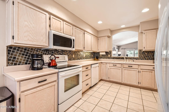 kitchen featuring white appliances, light countertops, arched walkways, a sink, and backsplash
