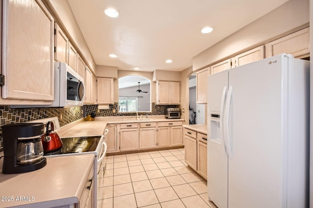 kitchen with a sink, light brown cabinets, white appliances, light countertops, and tasteful backsplash