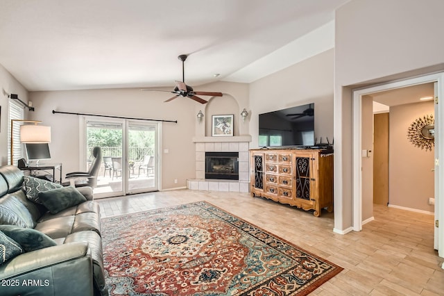 living area with lofted ceiling, wood finished floors, a fireplace, baseboards, and ceiling fan