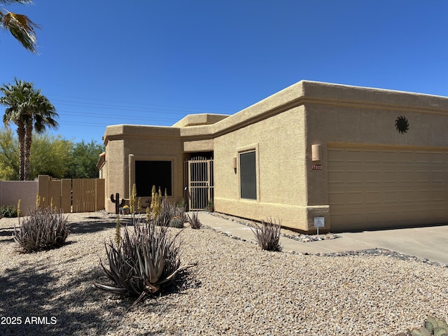 pueblo-style home featuring fence, a garage, stucco siding, a gate, and concrete driveway