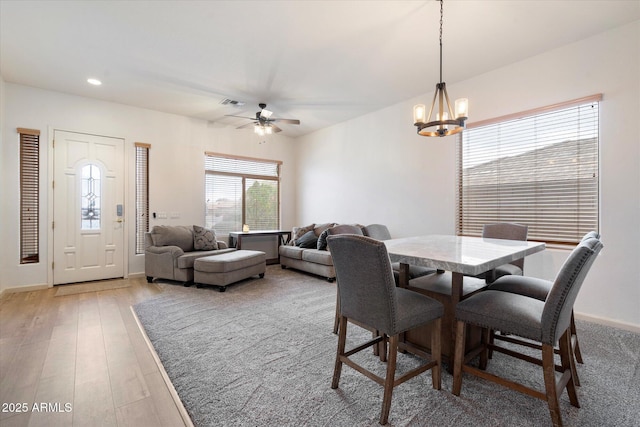 dining area featuring wood-type flooring and ceiling fan with notable chandelier