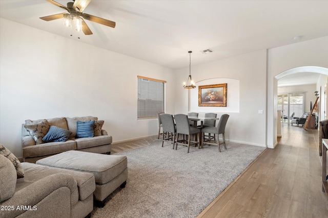 dining area with ceiling fan with notable chandelier and light hardwood / wood-style floors