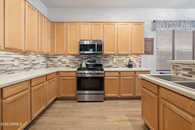 kitchen featuring sink, light hardwood / wood-style flooring, stainless steel appliances, tasteful backsplash, and light brown cabinetry