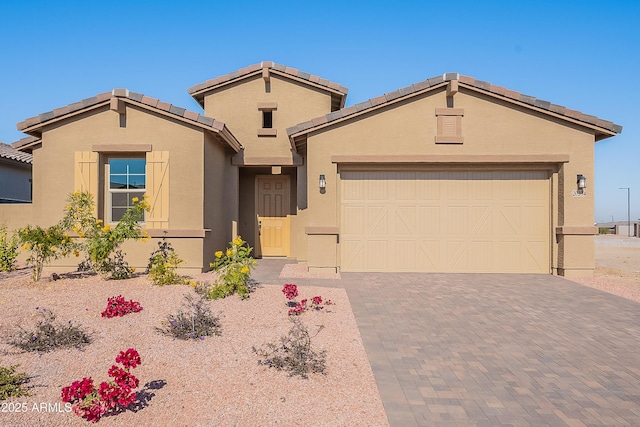 view of front of home with stucco siding, an attached garage, driveway, and a tiled roof