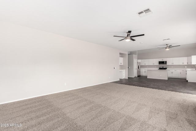 unfurnished living room with a ceiling fan, visible vents, dark colored carpet, and baseboards