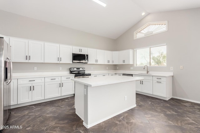 kitchen with appliances with stainless steel finishes, white cabinetry, light countertops, and a sink