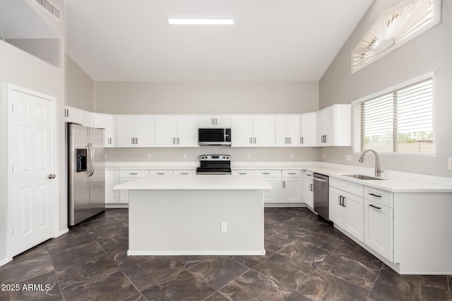 kitchen with a center island, light countertops, appliances with stainless steel finishes, white cabinetry, and a sink