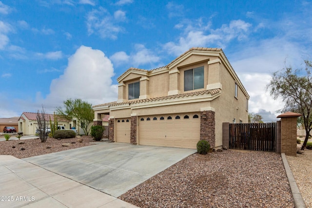 mediterranean / spanish home with an attached garage, stucco siding, concrete driveway, stone siding, and a tiled roof