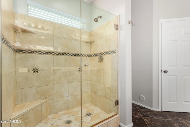 full bathroom with a shower stall and baseboards