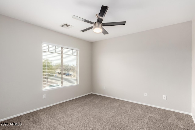 carpeted spare room featuring visible vents, baseboards, and ceiling fan