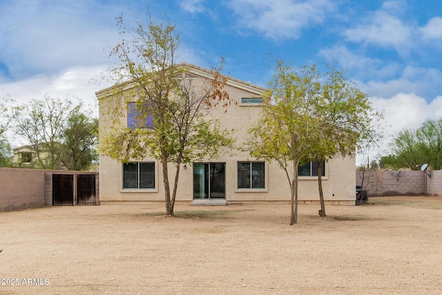 rear view of property with stucco siding and fence