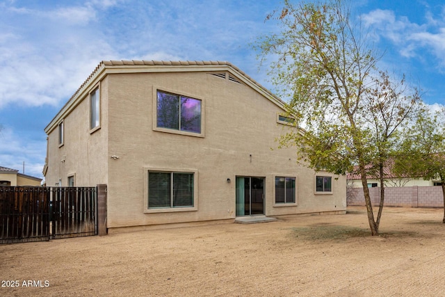 back of house featuring a tiled roof, a fenced backyard, and stucco siding