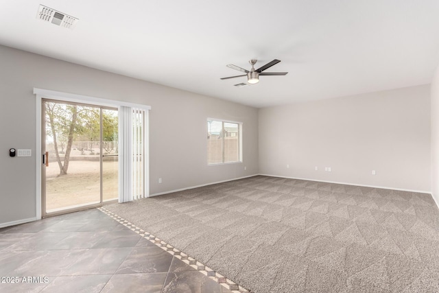 carpeted spare room with visible vents, a ceiling fan, and baseboards