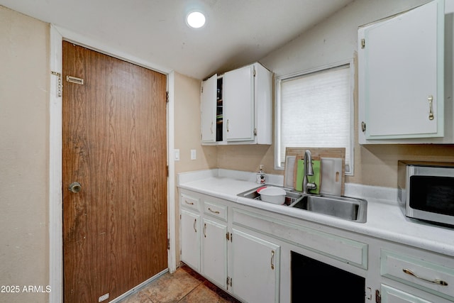 kitchen featuring white cabinetry, sink, and light tile patterned flooring