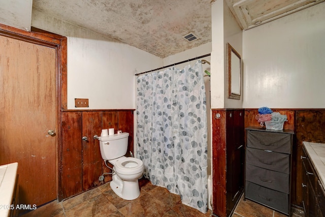 bathroom featuring curtained shower, wooden walls, and toilet