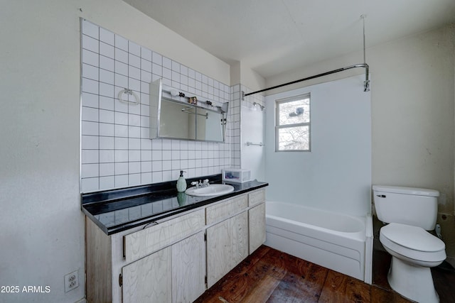 full bathroom featuring wood-type flooring, backsplash, tiled shower / bath combo, vanity, and toilet