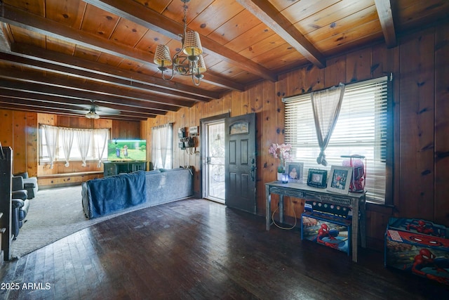 interior space featuring beam ceiling, dark wood-type flooring, wooden walls, and ceiling fan