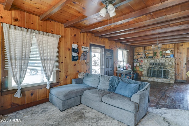 living room featuring beam ceiling, wood ceiling, a stone fireplace, and wood walls