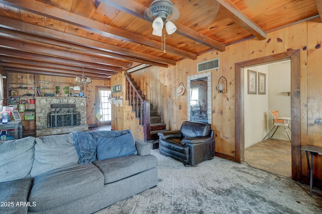 living room featuring beam ceiling, wood ceiling, a stone fireplace, and wood walls