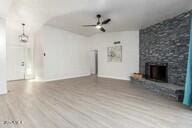 unfurnished living room with hardwood / wood-style floors, ceiling fan, and a large fireplace