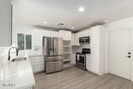 kitchen featuring white cabinetry, sink, light hardwood / wood-style flooring, and appliances with stainless steel finishes