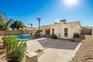 rear view of property with a fenced in pool and a patio area