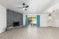 unfurnished living room with ceiling fan, a large fireplace, and wood-type flooring