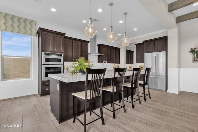 kitchen with light countertops, dark brown cabinets, wall chimney range hood, and stainless steel appliances