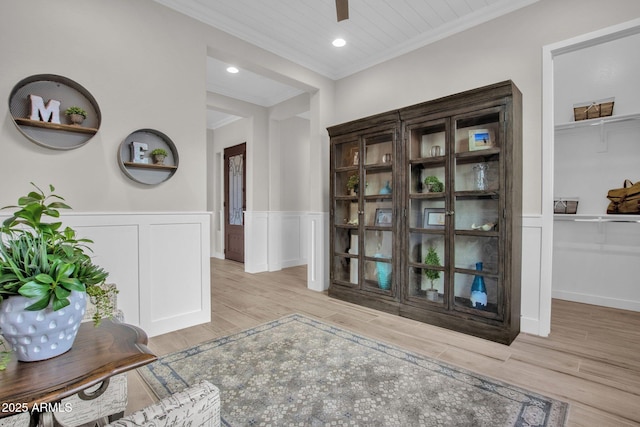 interior space featuring recessed lighting, ornamental molding, wood finished floors, and a wainscoted wall