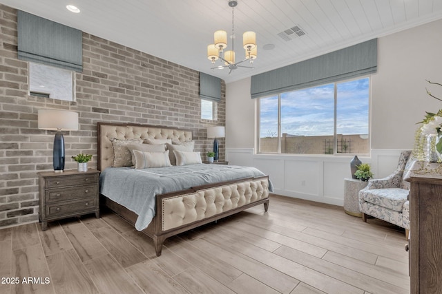 bedroom with visible vents, an inviting chandelier, light wood-style flooring, and a wainscoted wall