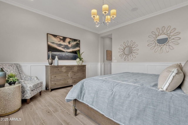 bedroom with wainscoting, wood finished floors, an inviting chandelier, ornamental molding, and a decorative wall