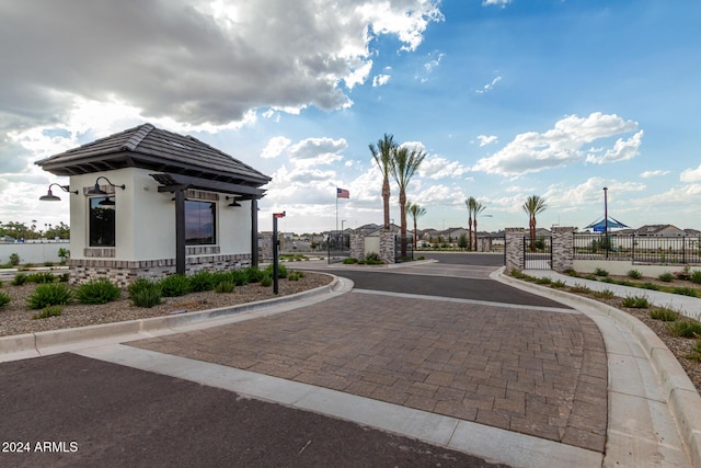 view of street with a gate, a gated entry, and curbs