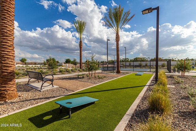 view of property's community with a tennis court and fence