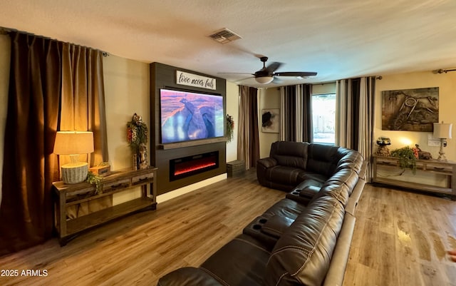 home theater with visible vents, ceiling fan, wood finished floors, and a fireplace