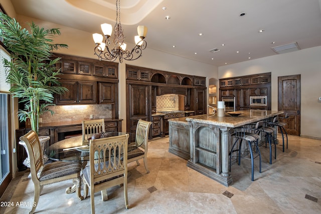 kitchen featuring a large island, dark brown cabinets, light stone countertops, and appliances with stainless steel finishes