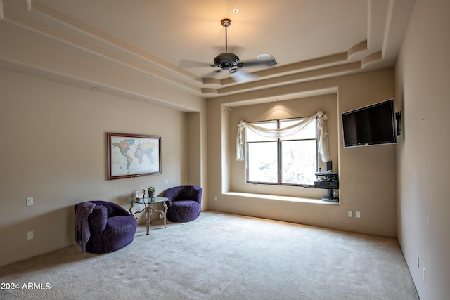 unfurnished room featuring ceiling fan, a raised ceiling, and light carpet