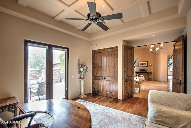 office area featuring coffered ceiling, hardwood / wood-style floors, ceiling fan with notable chandelier, and french doors