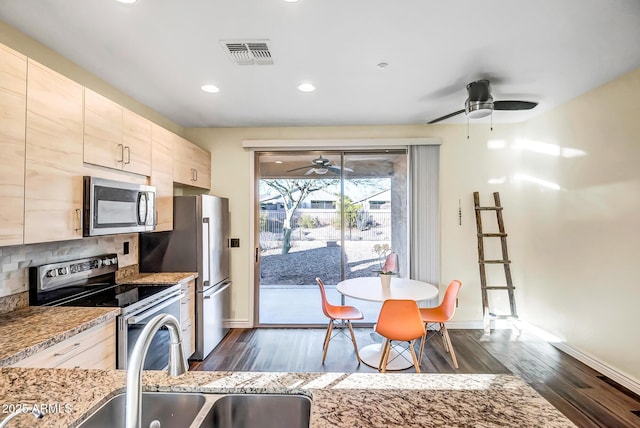 kitchen featuring sink, dark wood-type flooring, stainless steel appliances, light stone counters, and tasteful backsplash