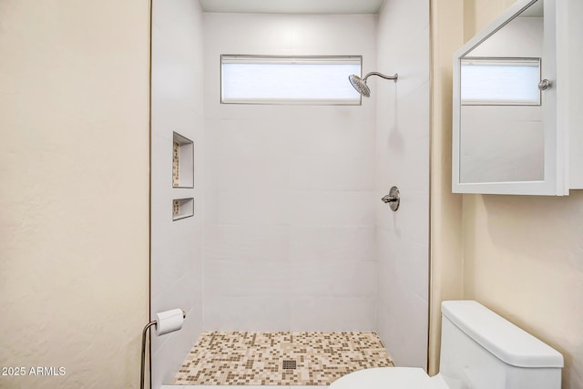 bathroom featuring a tile shower and toilet