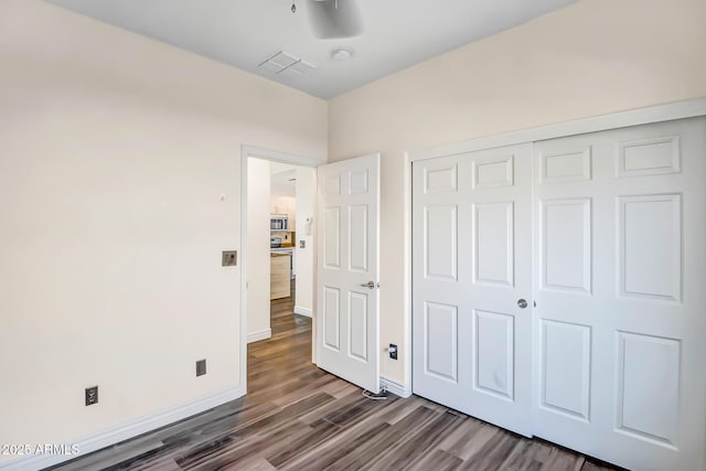 unfurnished bedroom with dark hardwood / wood-style floors and a closet